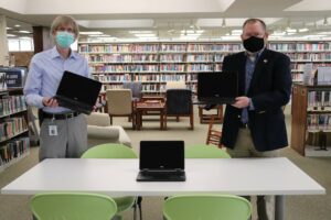 two men in library holding computers