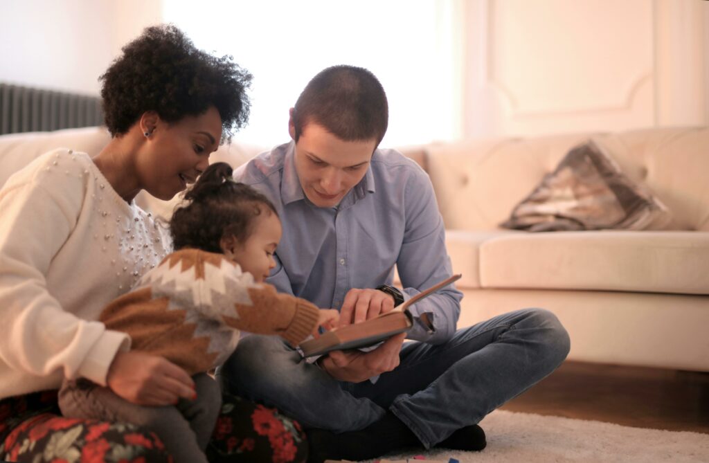 Two adults reading to young child