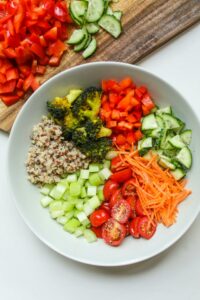 bowl filled with portions of grains and vegetables in various colors.