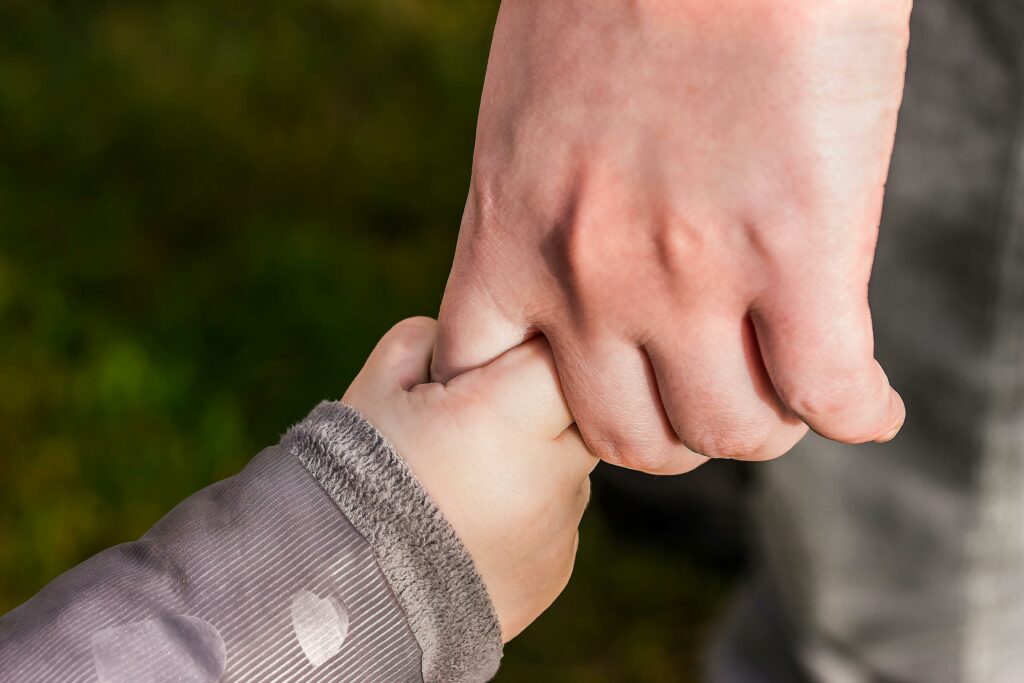 zoomed in photo of young child holding adult hand