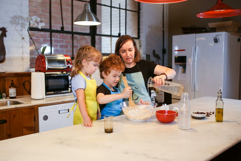 mother and two children mixing items in glass bowl at the counter of a kitchen