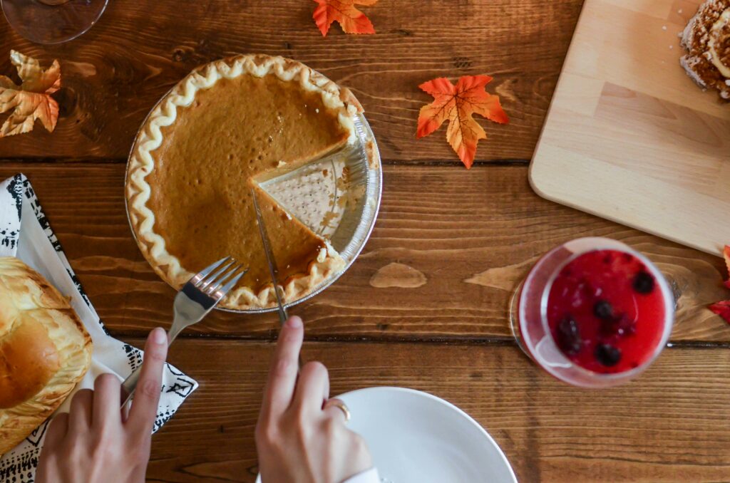 hands cutting into pumpkin pie missing a slice