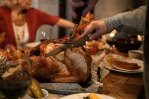 image of hands holding utensils while carving a turkey